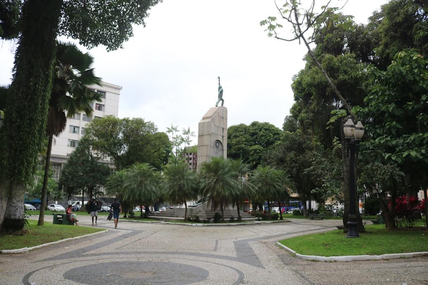 vista geral da praça com árvores e monumento ao fundo. #paratodosverem