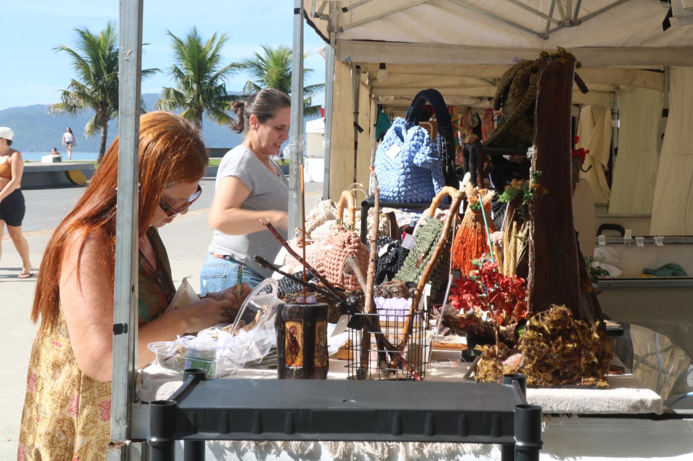pessoas visualizam artigos em feira de economia criativa #paratodosverem