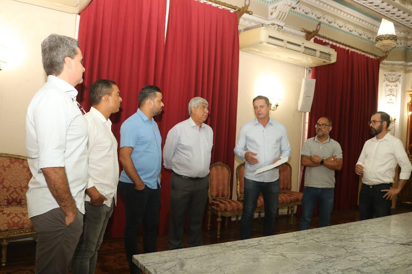 sete homens atrás de uma mesa, todos em pé. Entre eles estão o prefeito e o presidente da câmara 