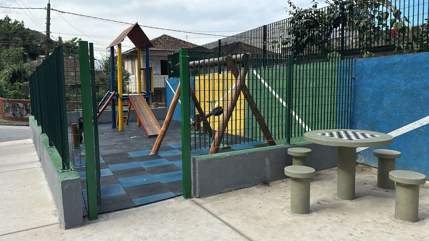 playground com escorregador e balanço. Mesas de jogos à frente. #paratodosverem