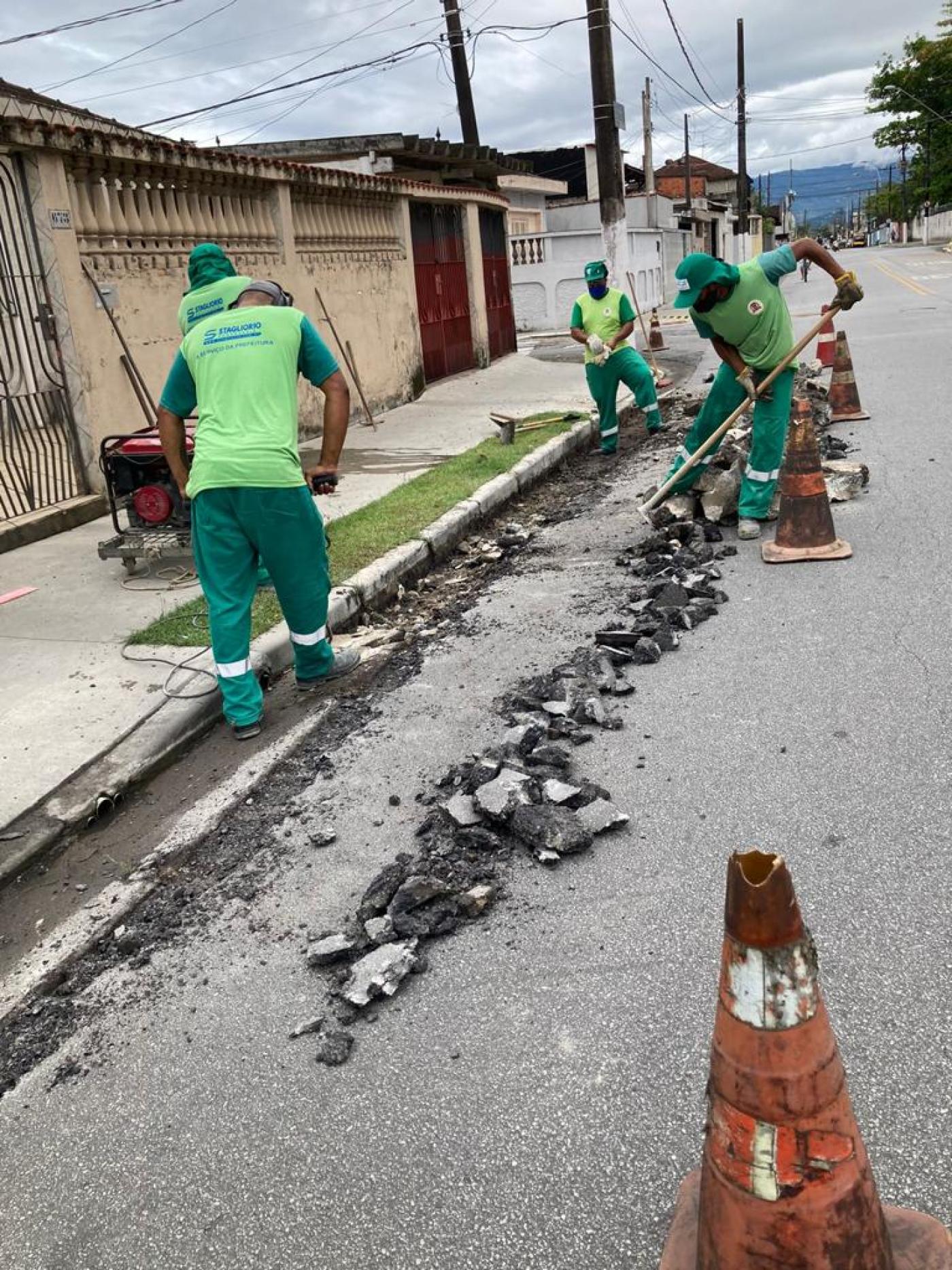 homens estão trabalhando na reconstrução de sarjeta. Trecho da rua junto à guia está quebrado. #paratodosverem