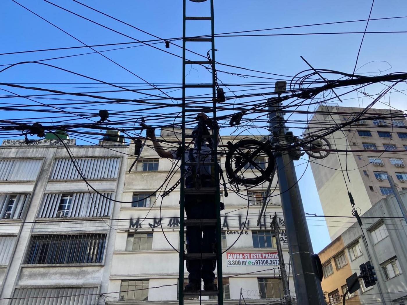 homem em escada remove fios aéreos. #paratodosverem