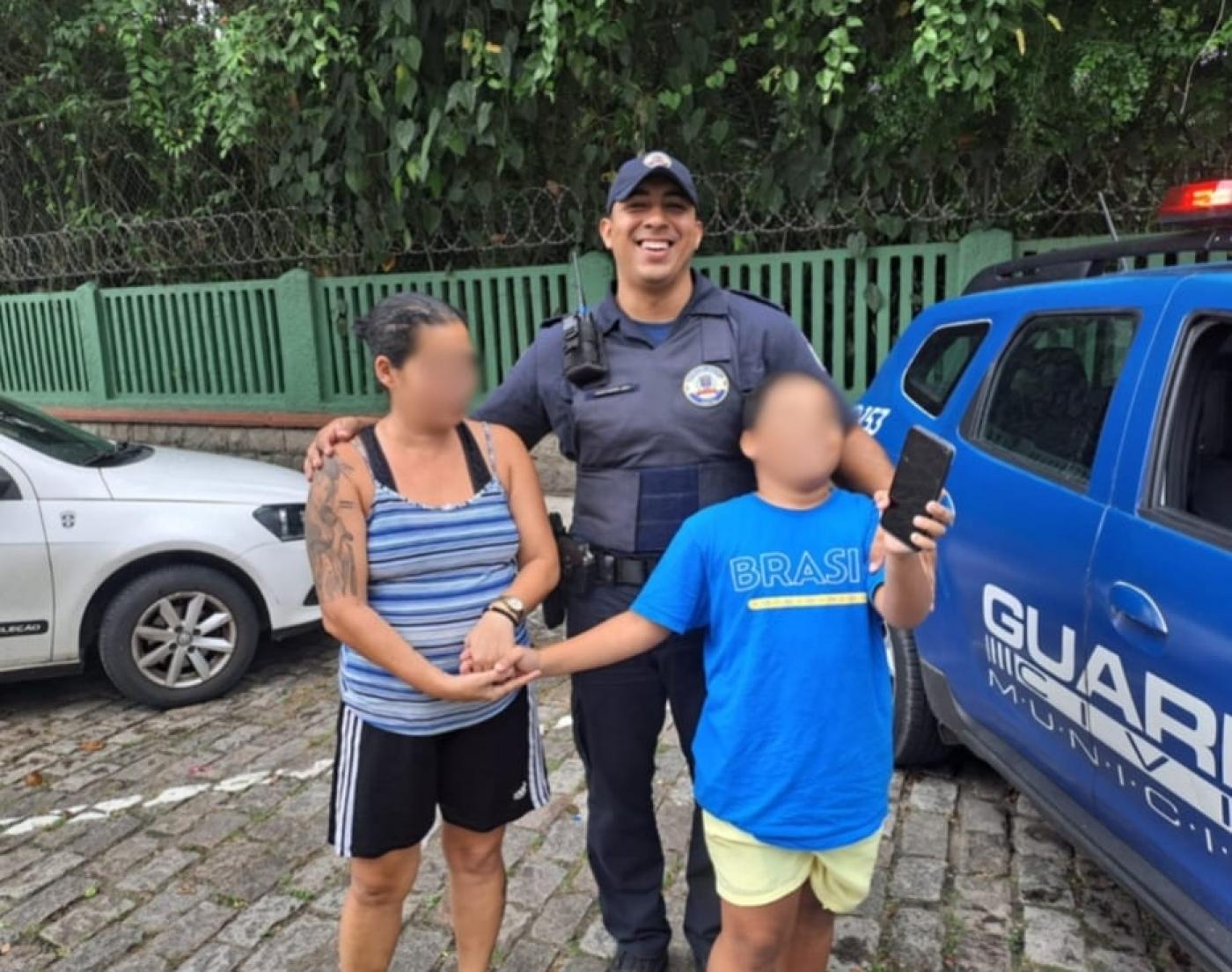 a mãe, o guarda e o menino juntos em frente ao orquidário. #paratodosverem