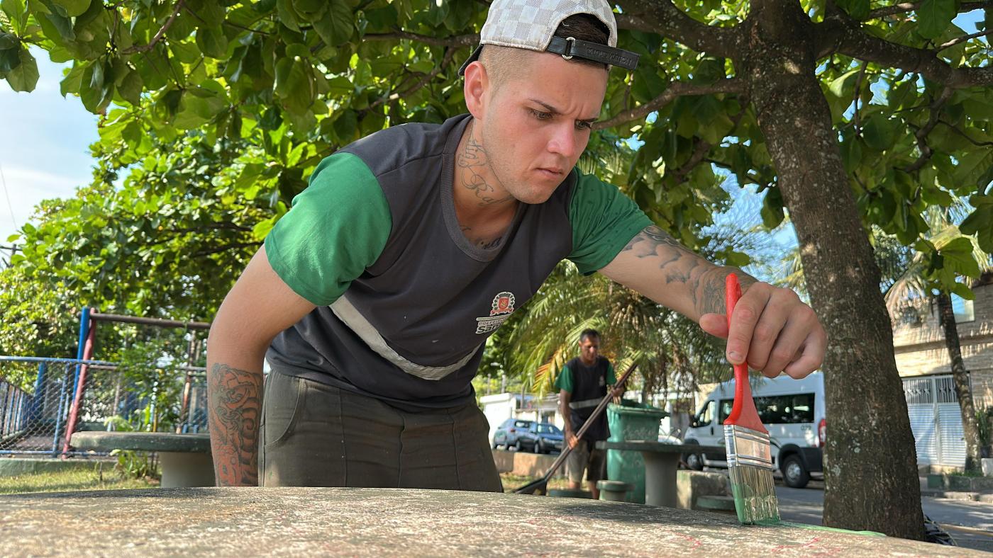 rapaz pintando trecho da praça #paratodosverem