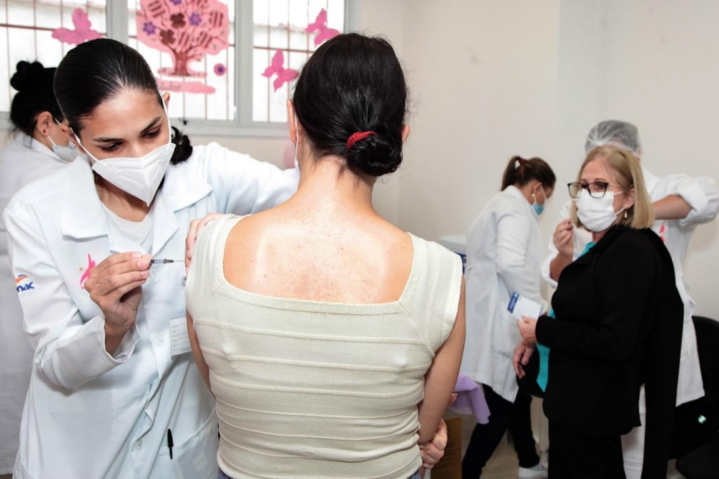 Enfermeira aplica vacina em mulher #paratodosverem