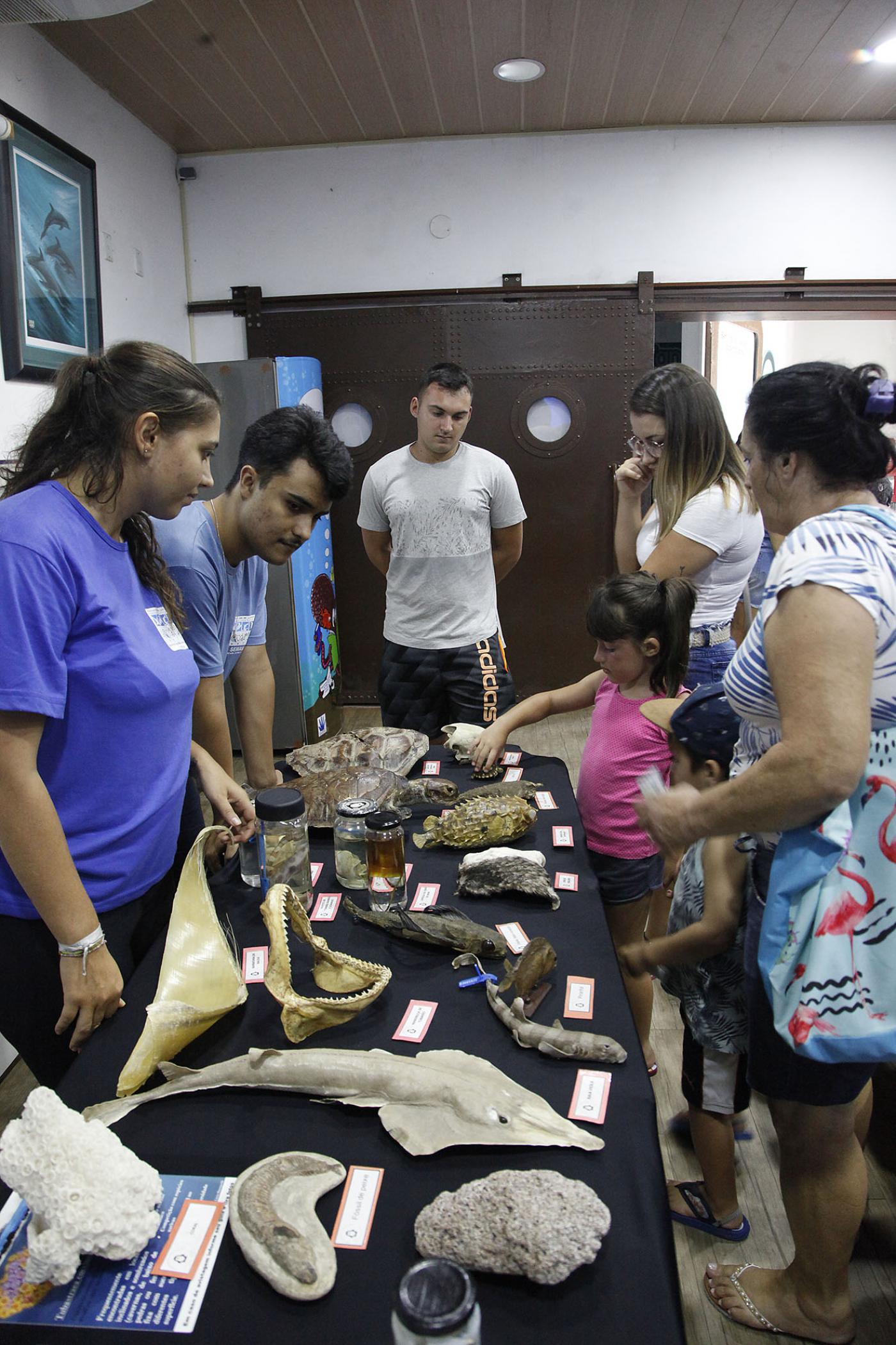 Pessoas estão em pé em torno de mesa com peças marinhas