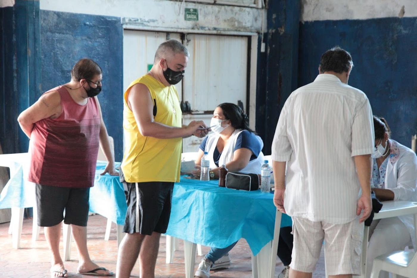 pessoas preenchem ficha em posto de vacinação #paratodosverem
