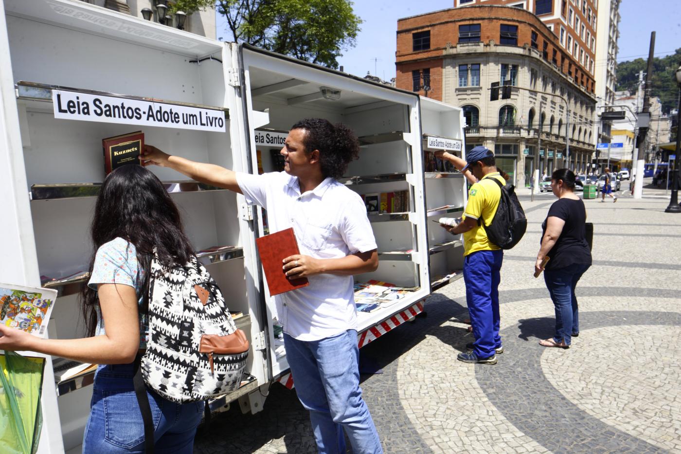 pessoas pegam livros no estande do projeto #pracegover 