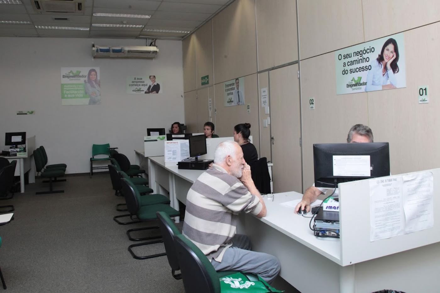 Senhor, sentado, é atendido por profissional da Sala do Empreendedor. #pratodosverem