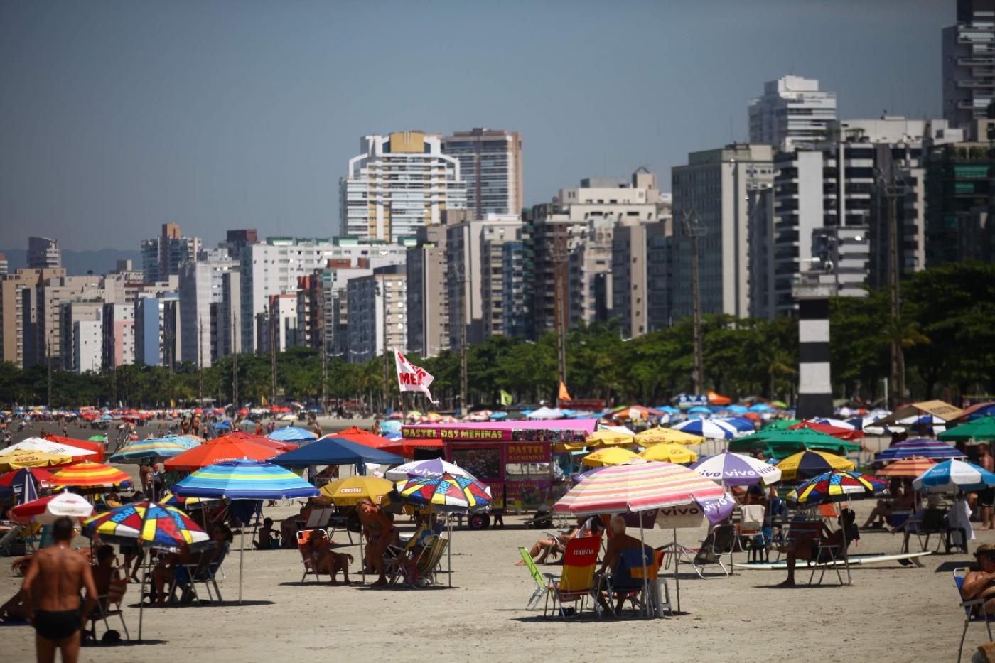 praia cheia com vários guarda-sóis #paratodosverem