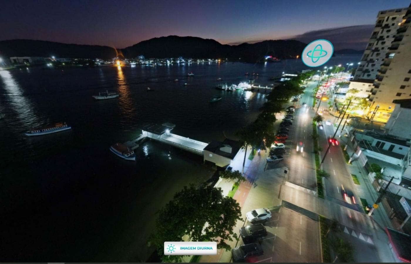 vista aérea da ponta da praia à noite, como o mar à esquerda, a avenida ao centro e os prédios à direito. Em primeiro plano, à esquerda, o deck do pescador. #paratodosverem