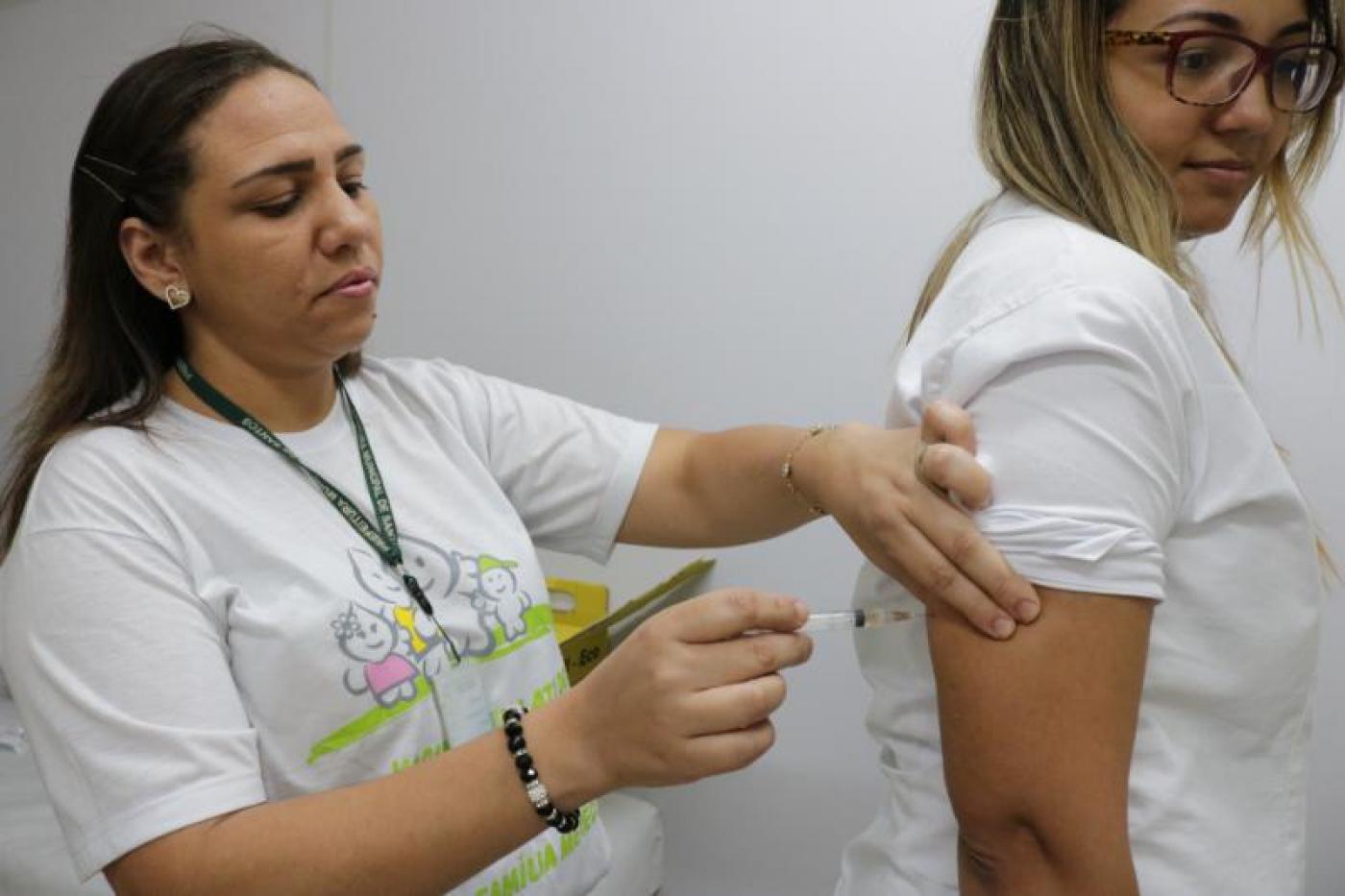 Profissional de saúde aplica vacina em mulher. #pracegover