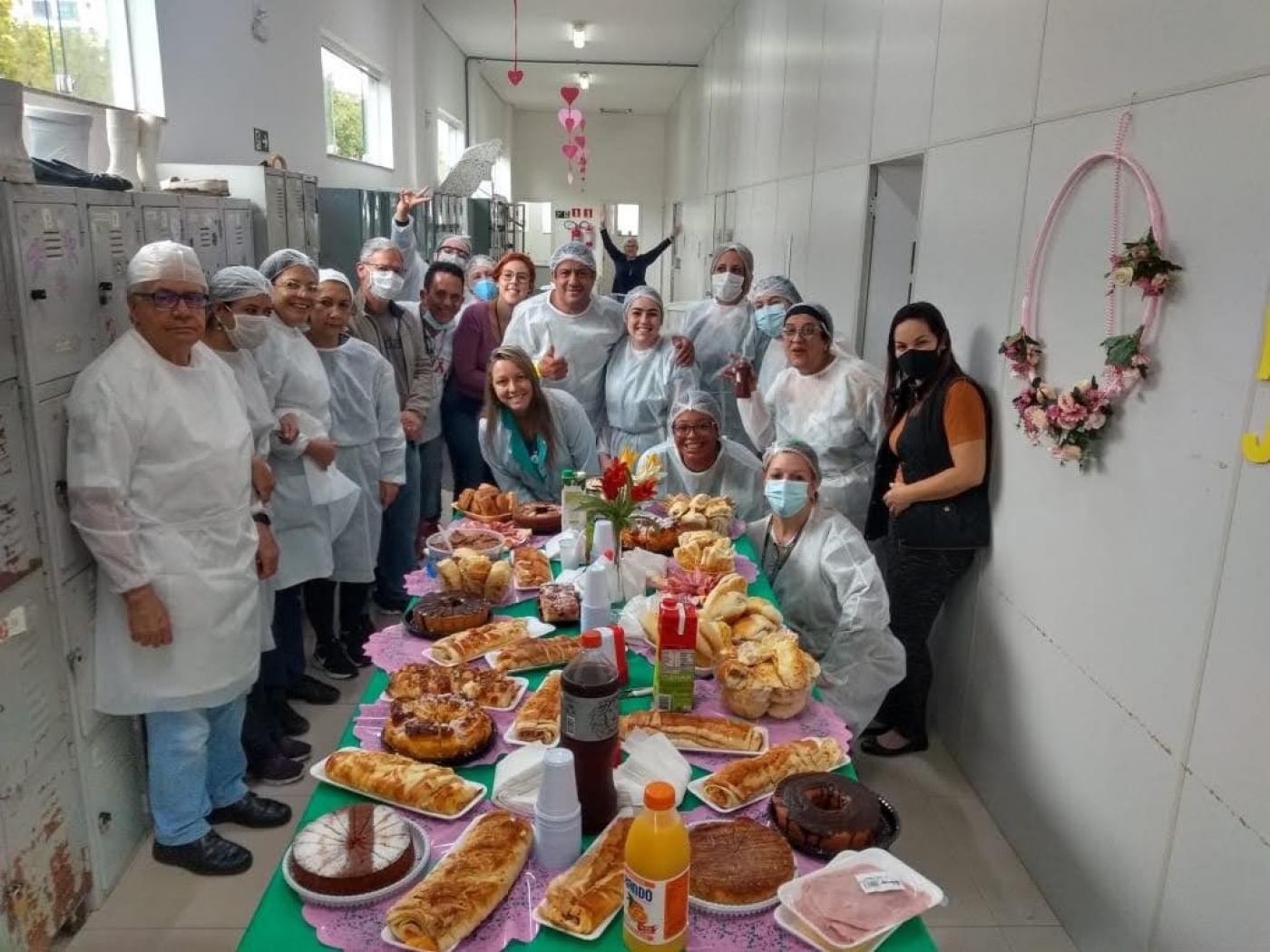 Funcionários de saúde estão reunidos para foto em torno de mesa. #Paratodosverem