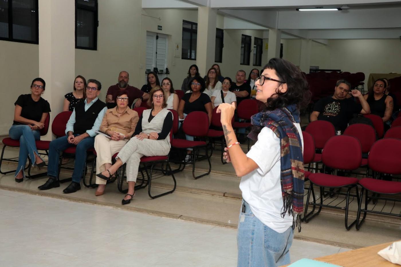 mulher fala para pessoas no auditório #paratodosverem