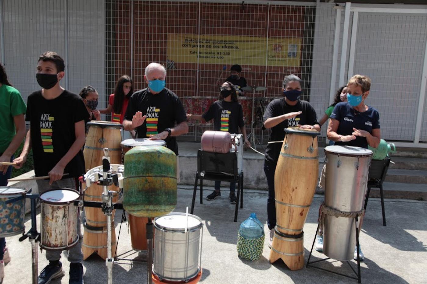 Os patriarcas da família tocaram instrumentos de percussão com crianças do Arte no Dique. #pracegover