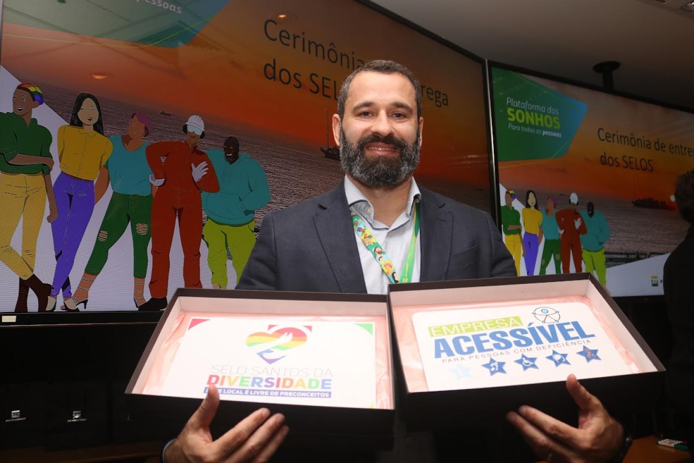 homem mostra os dois selos que a empresa ganhou #paratodosverem