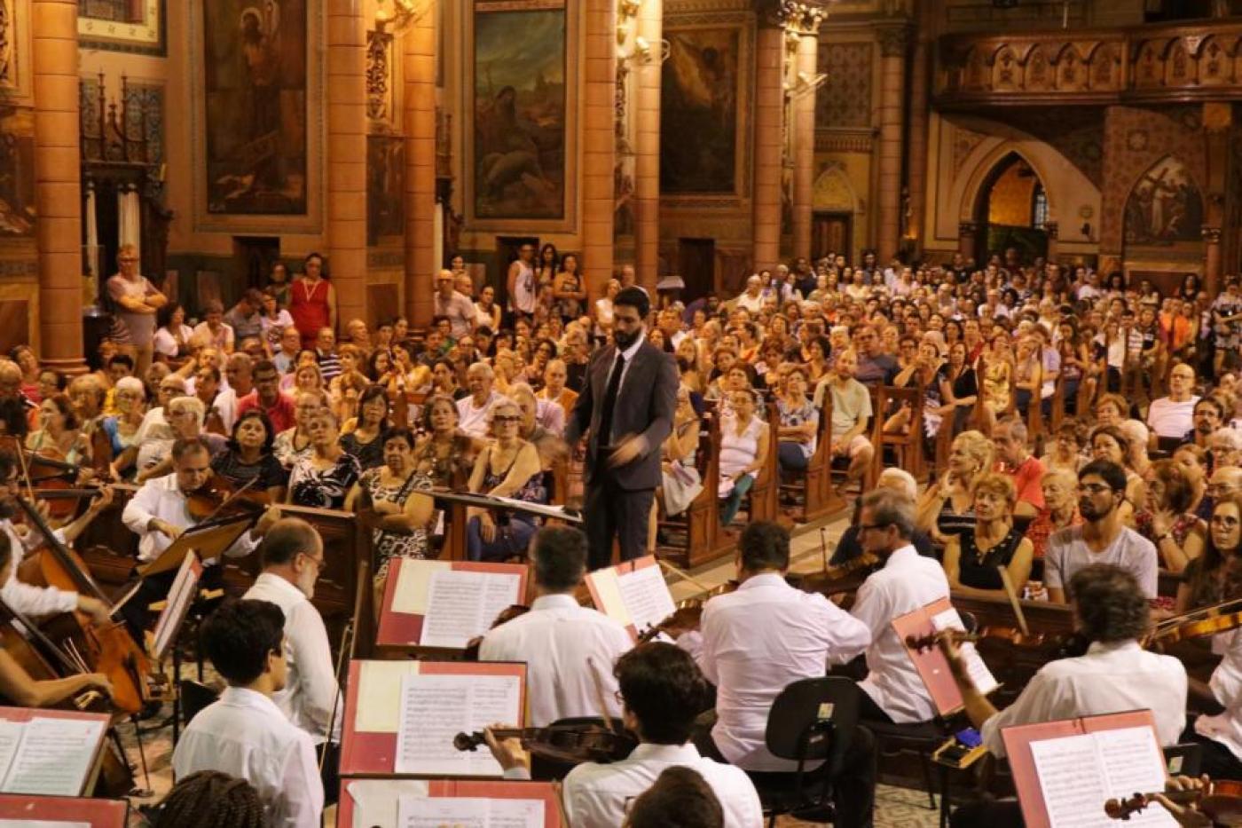 músicos de costas para a foto tocam em igreja lotada. #paratodosverem 