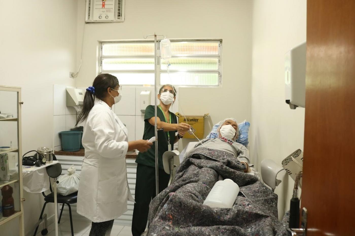 duas mulheres estão atendendo homem acabamado em hospital. #paratodosverem