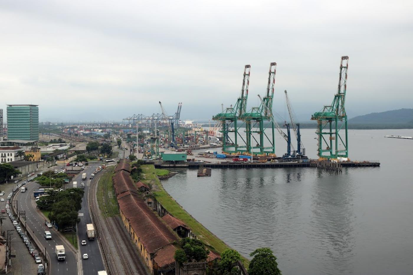 vista geral do porto, com porteineres adentrando em deck no mar, as avenidas e prédios. #paratodosverem