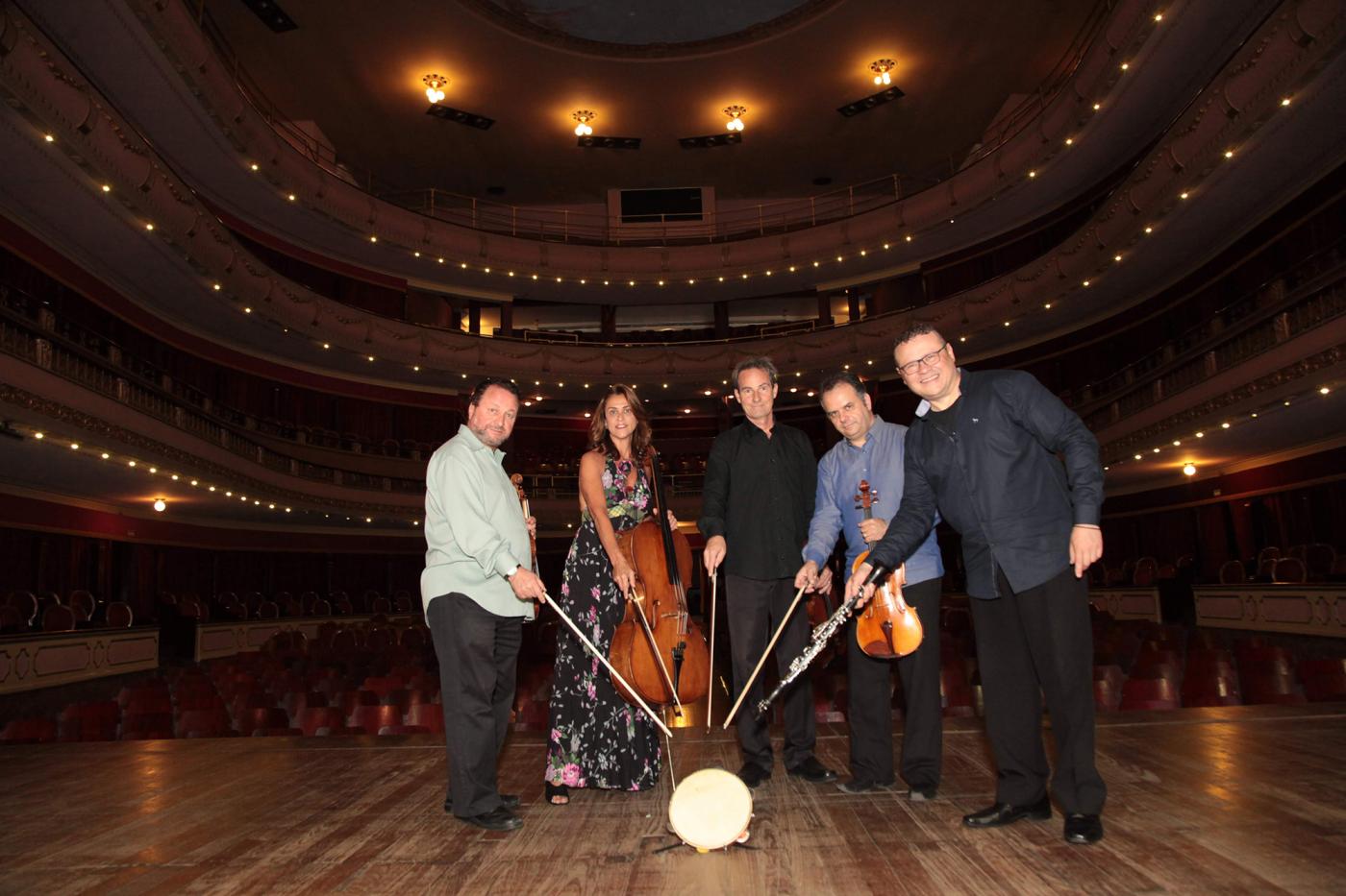 membros do quarteto estão com baquetas unidas em palco #pracegover 