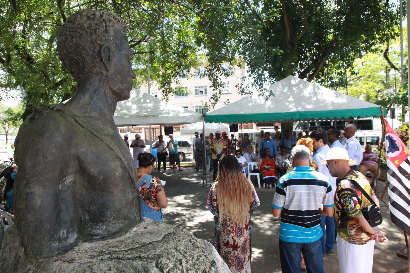 Pessoas estão em círculo durante homenagem a Zumbi #pracegover 