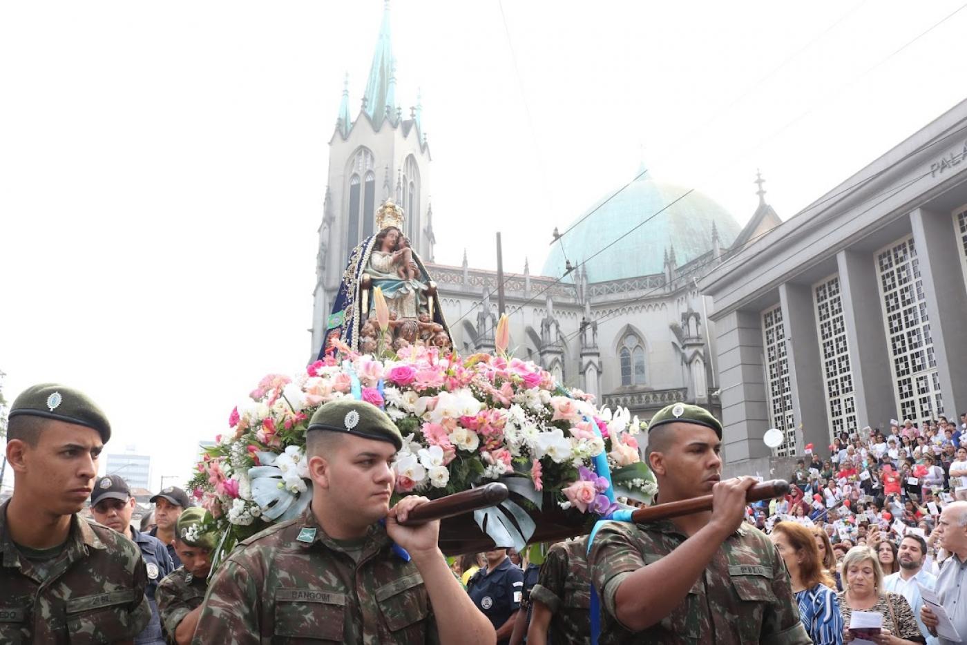 soldados carregam imagem com catedral ao fundo #paratodosverem