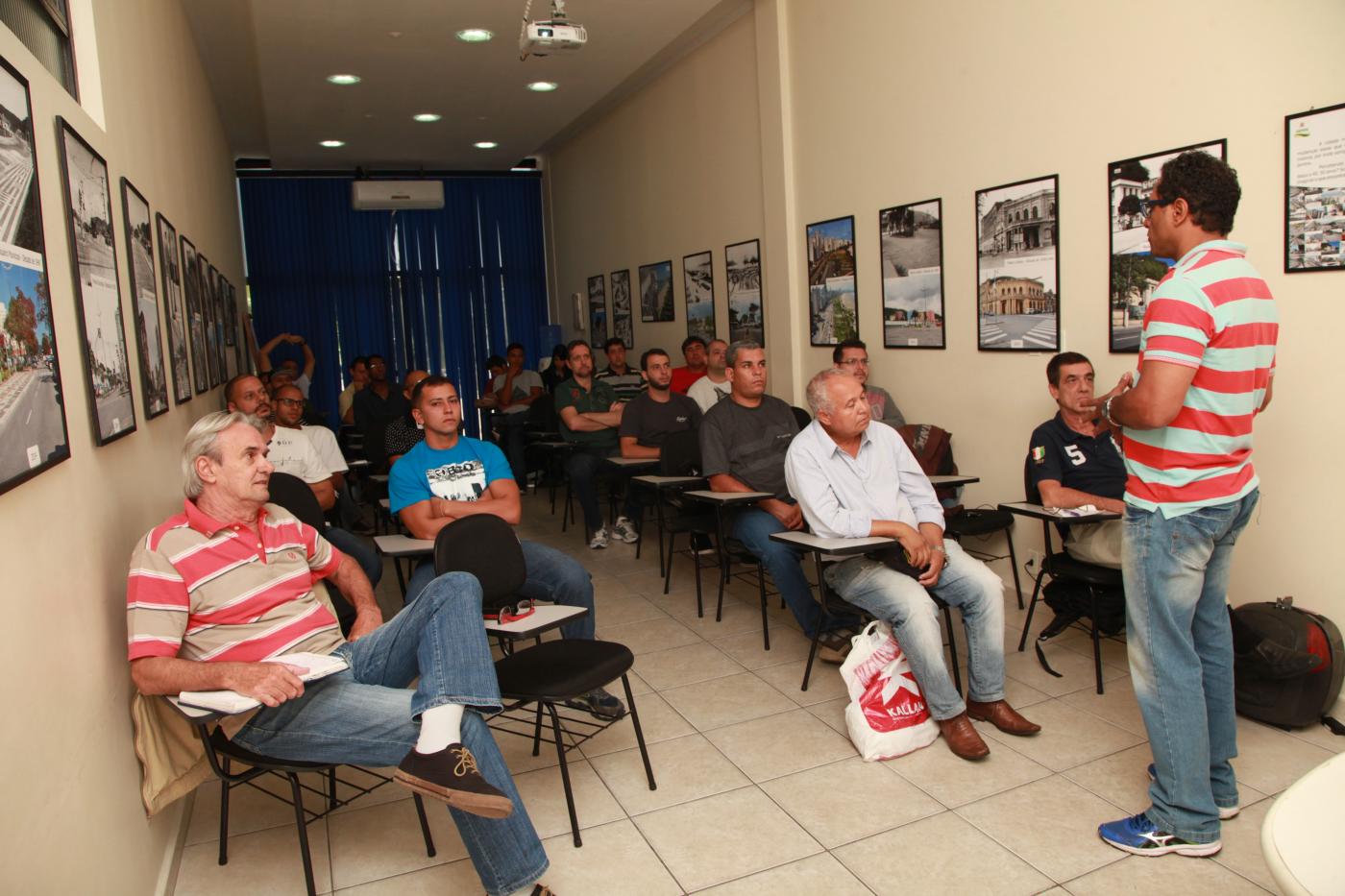 alunos estão sentados em classe olhando professor falar em pé #pracegover 