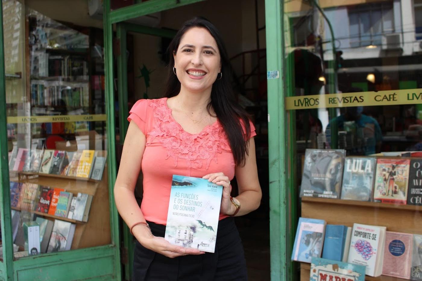 autora segura livro com livraria ao fundo #paratodosverem