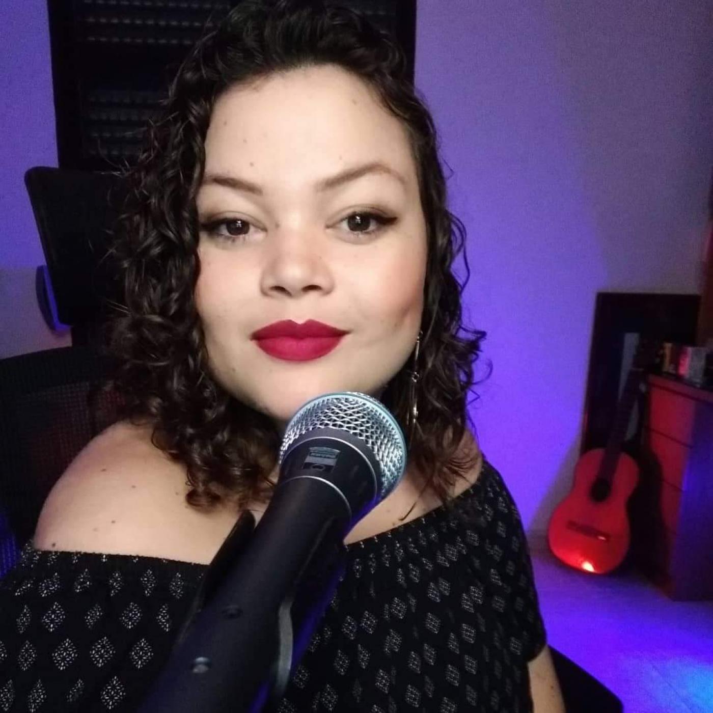 Cantora olhando para foto na frente de um microfone. #paratodosverem