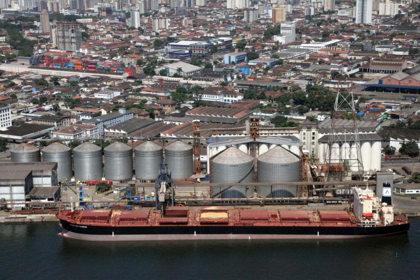 Vista aérea do porto com tanques e navio encostado em primeiro plano. #Paratodosverem