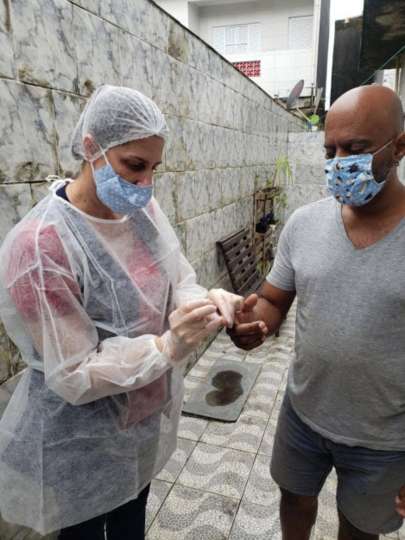 Profissional de saúde realiza coleta de sangue furando dedo de munícipe. #pracegover