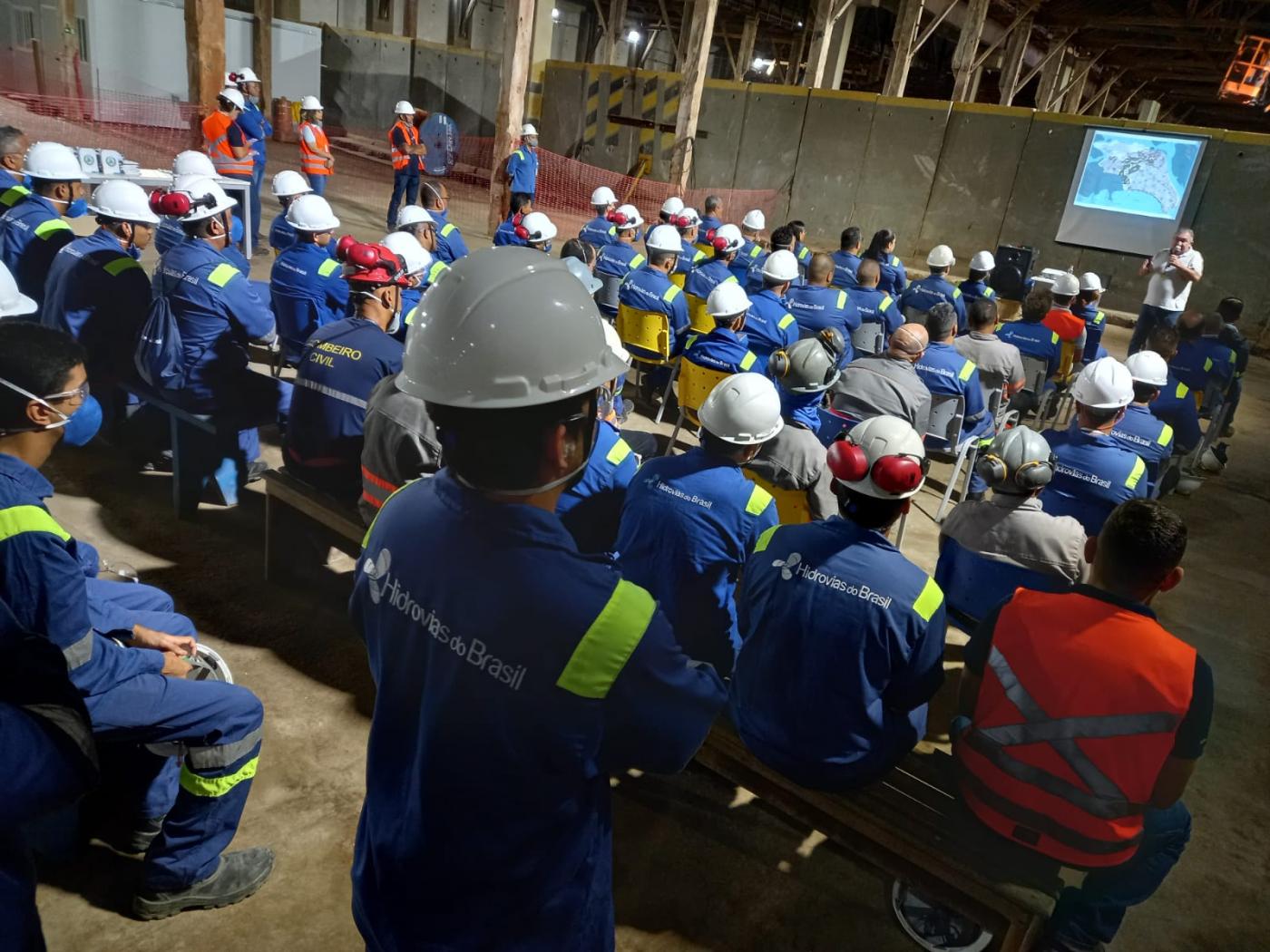 vários homens uniformizados e com capacete estão assistindo palestra. #paratodosverem