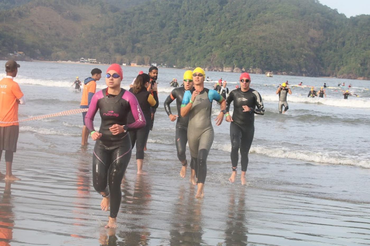 mulheres estão saindo do  mar, finalizando prova de natação. #paratodosverem