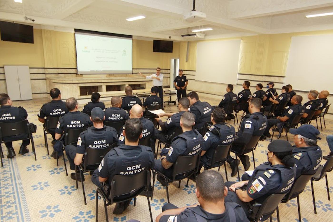 guardas estão sentados em auditório assistindo palestra. Todos estão de costas para a foto.. #paratodosverem