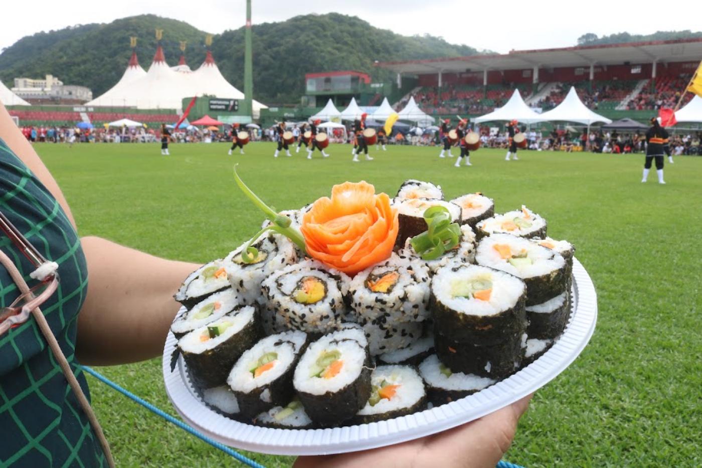 prato de comida japonesa com dança ao fundo #paratodosverem
