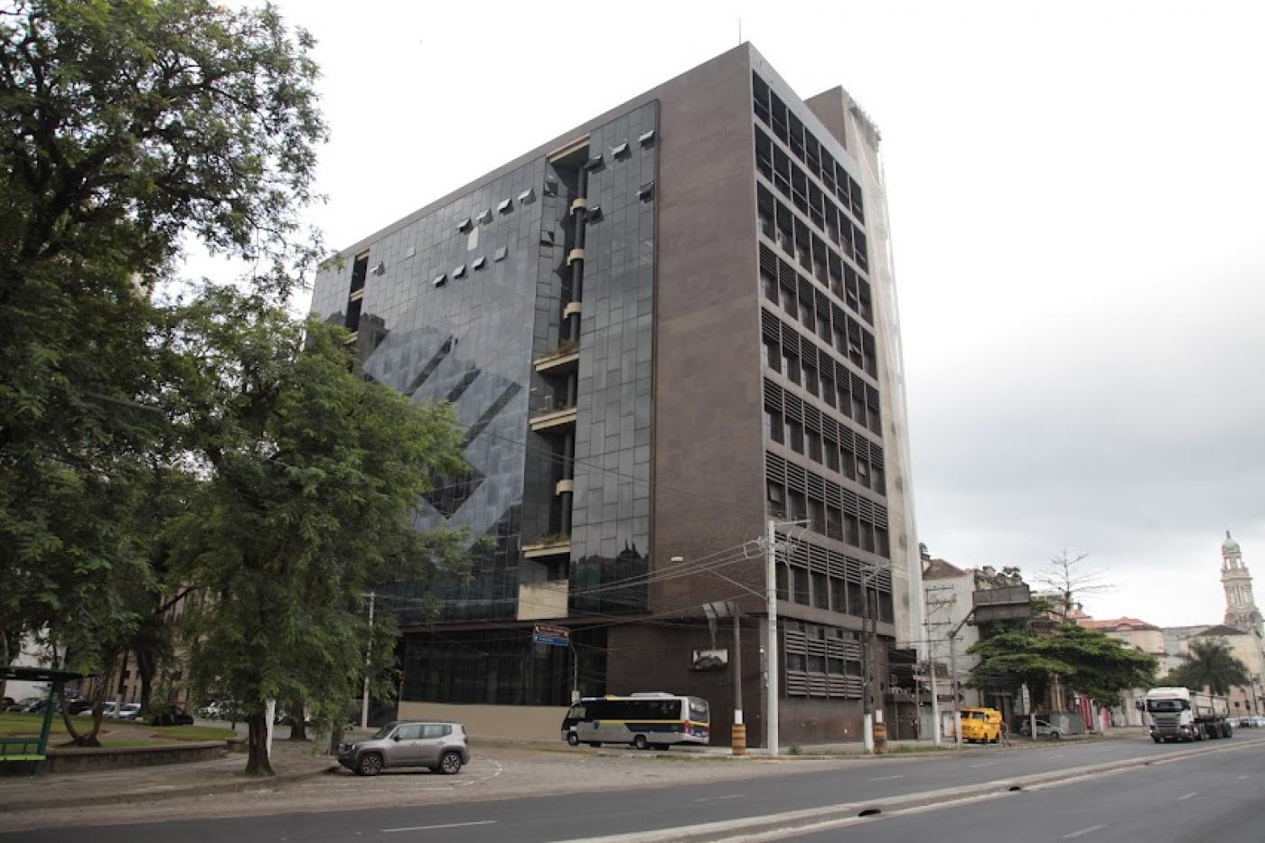 vista distante da fachada do prédio onde dicara a universidade, com grande avenida passando na frente. #paratodosverem