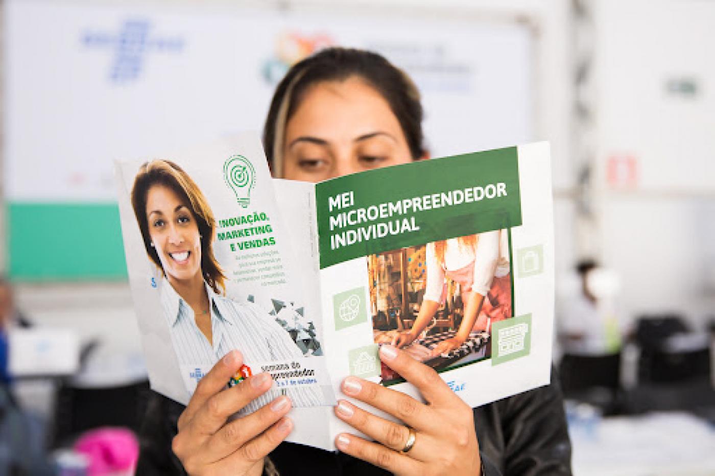 Jovem lê informativo sobre microempreendedor individual. #paratodosverem