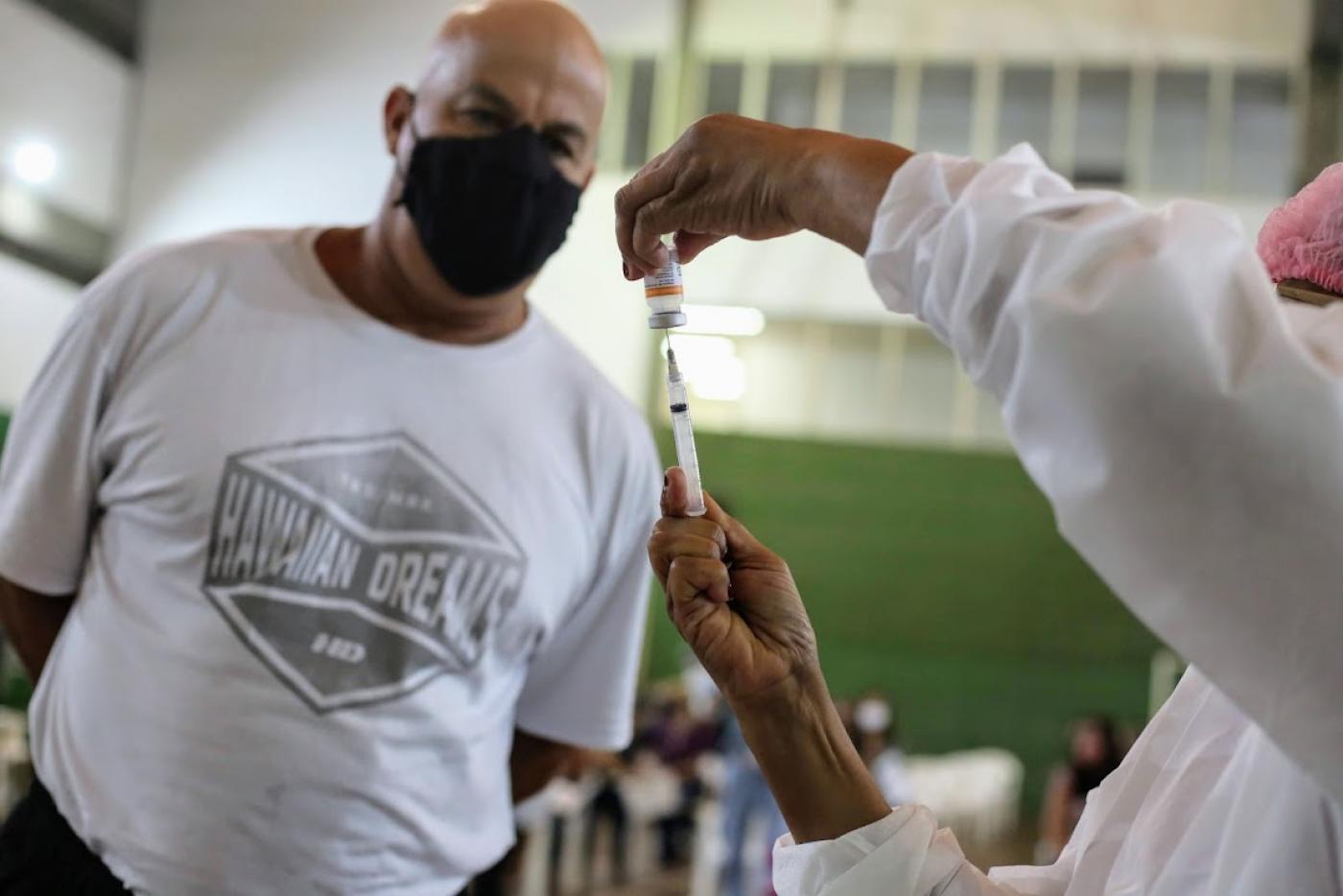 Homem observa mulher preparando a vacina #paratodosverem
