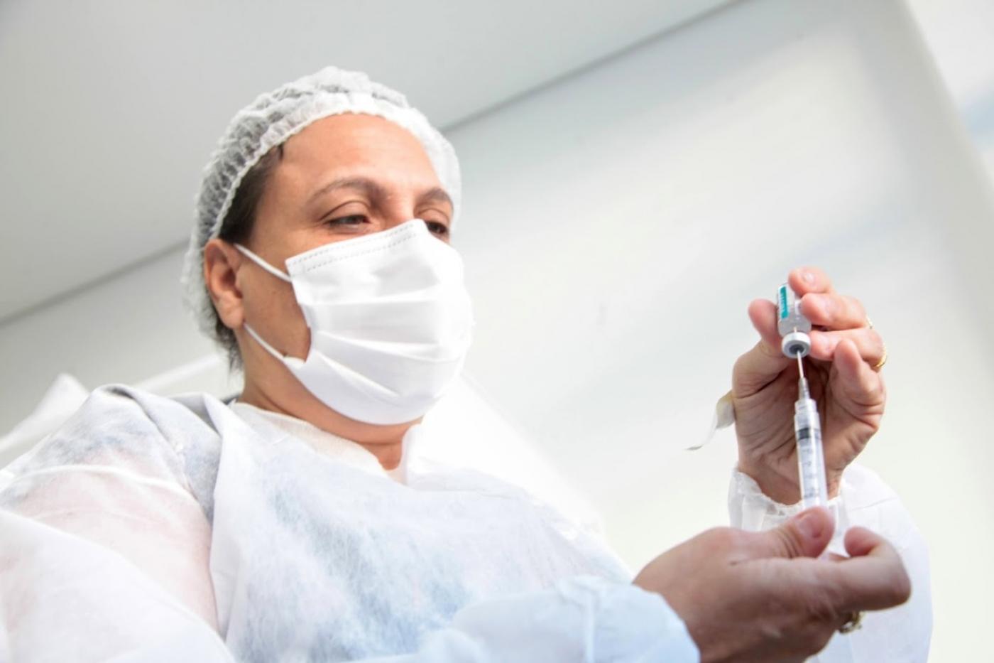 mulher insere imunizante em seringa. #paratodosverem