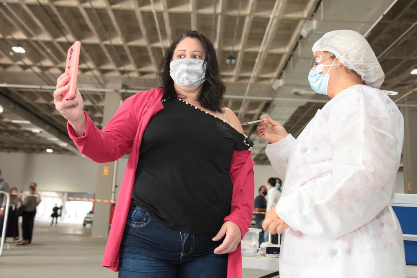 mulher tira selfie enquanto outra a vacina. #paratodosverem