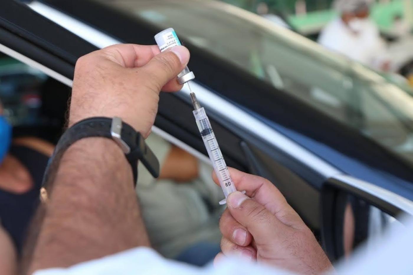 Uma mão está preparando uma injeção da vacina #paratodosverem