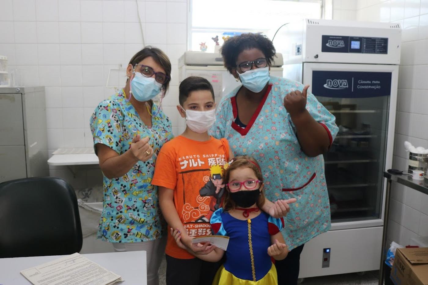 enfermeiras e duas crianças na sala de vacinação #paratodosverem