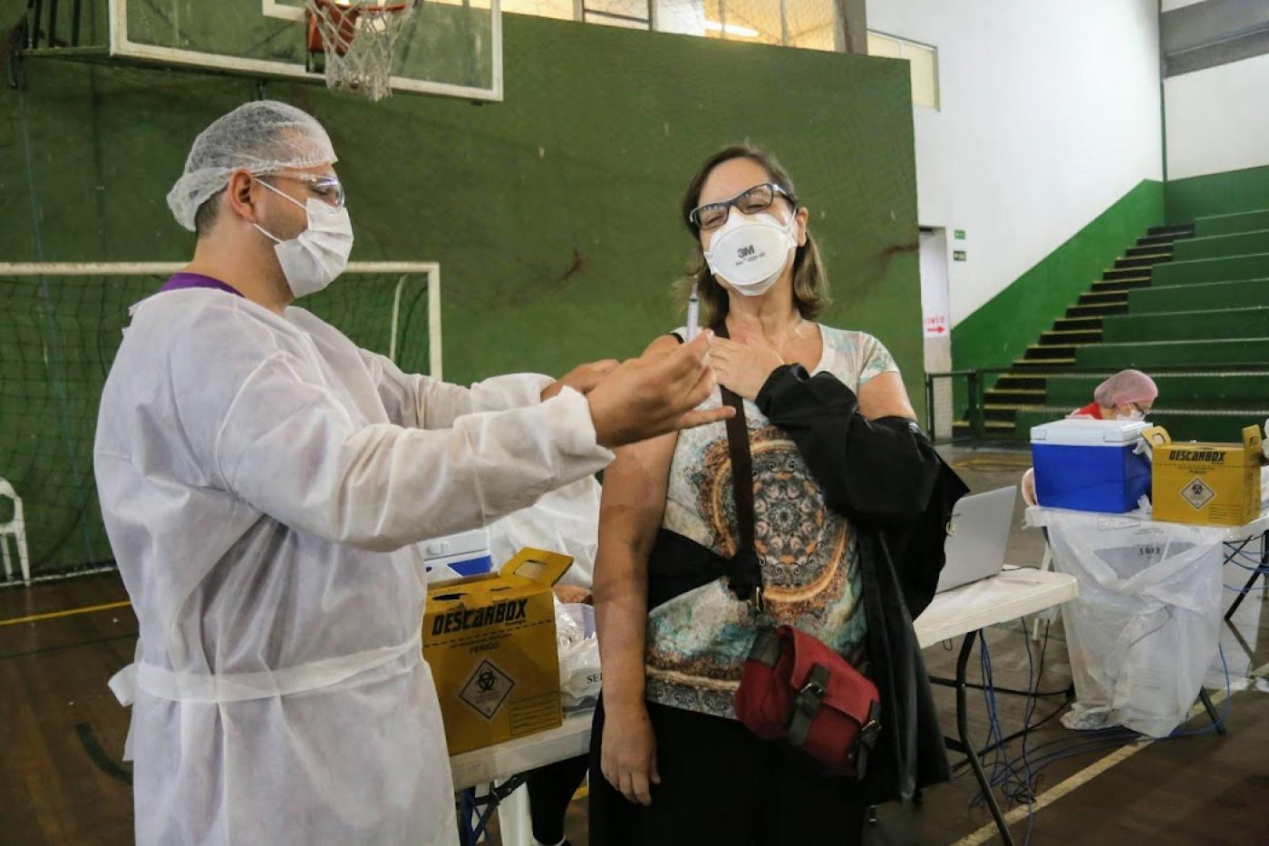 Enfermeiro mostra vacina para mulher #paratodosverem