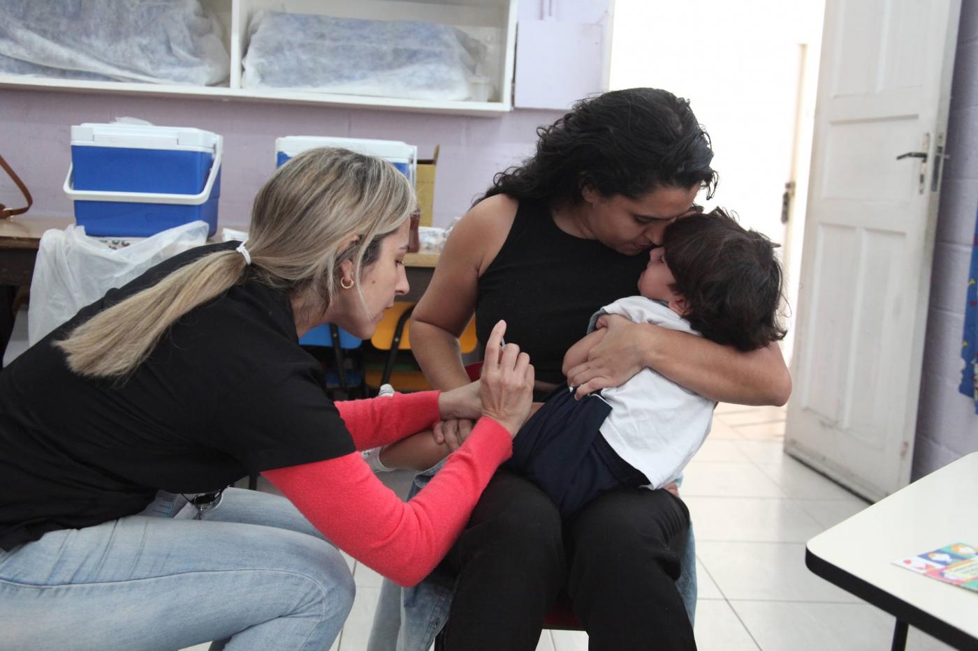 enfermeira vacina criança no colo da mãe. #paratodosverem