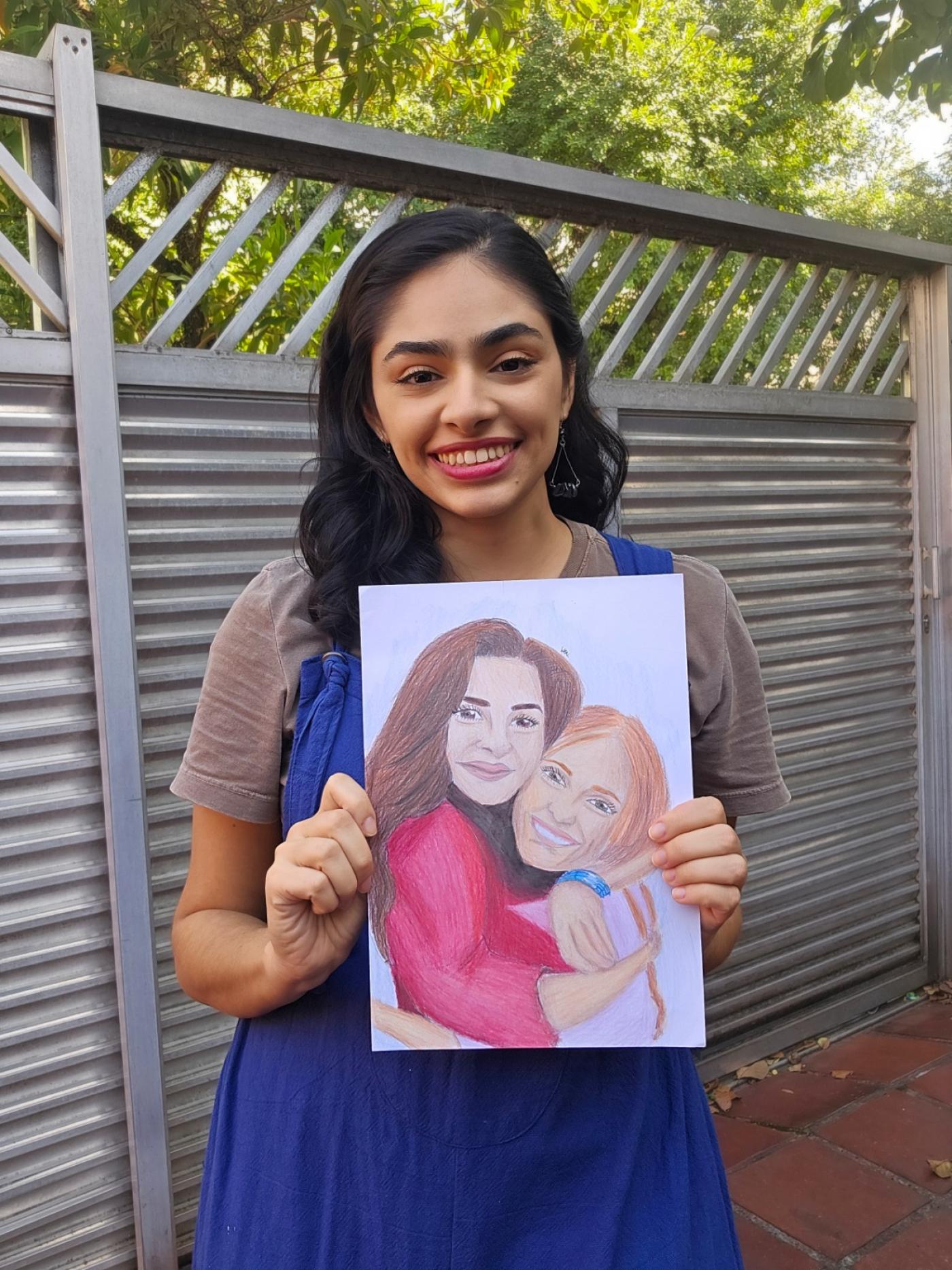 mulher sorri para a foto segurando um desenho. #paratodosverem 