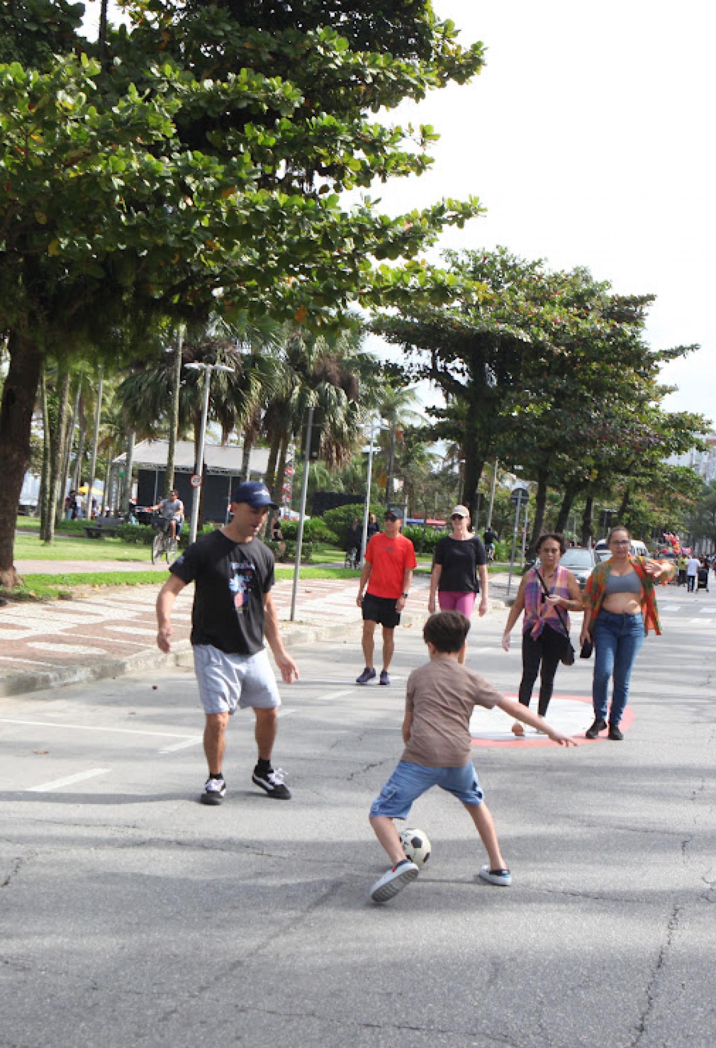 pessoas na orla caminhando e jogando futebol #paratodosverem 