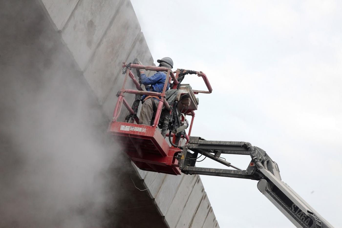 Superfície lateral de viaduto é lixada e polida. #paratodosverem