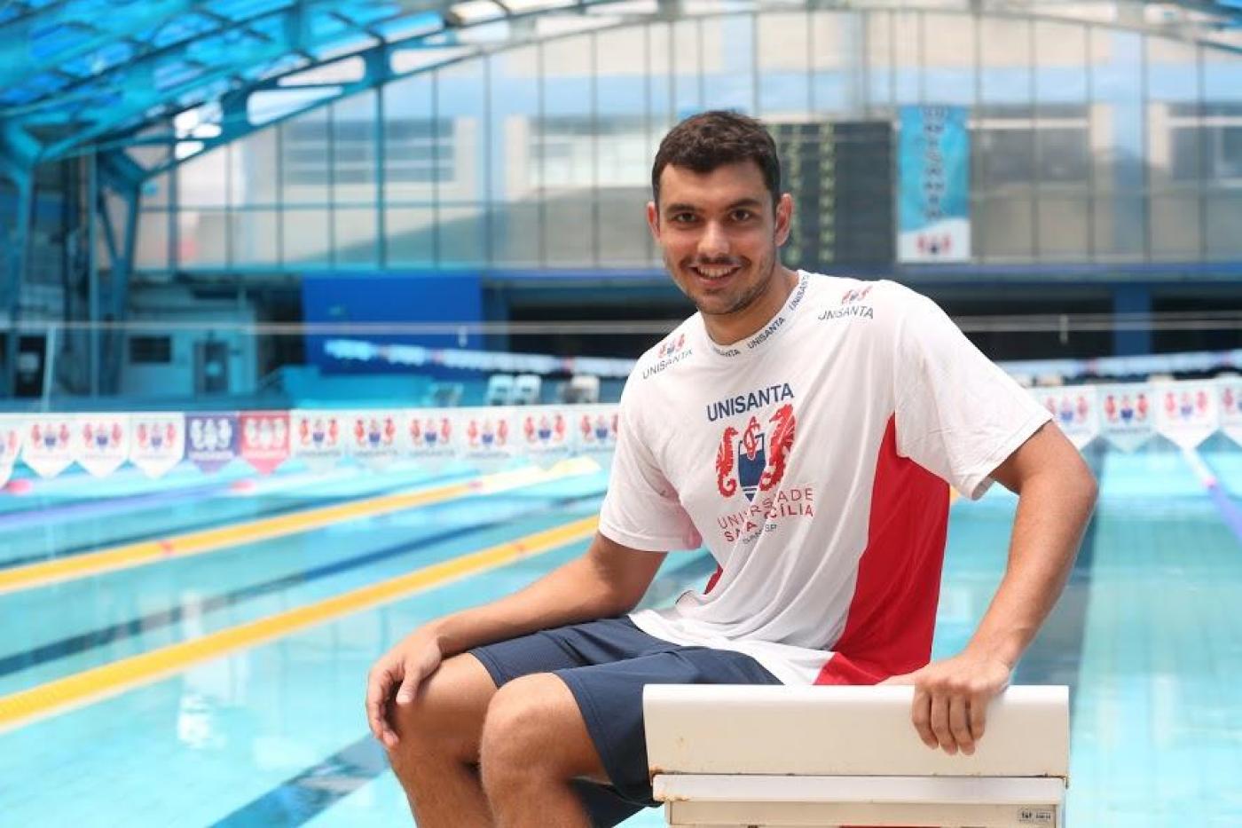 Nadador sentado em frente a piscina #paratodosverem