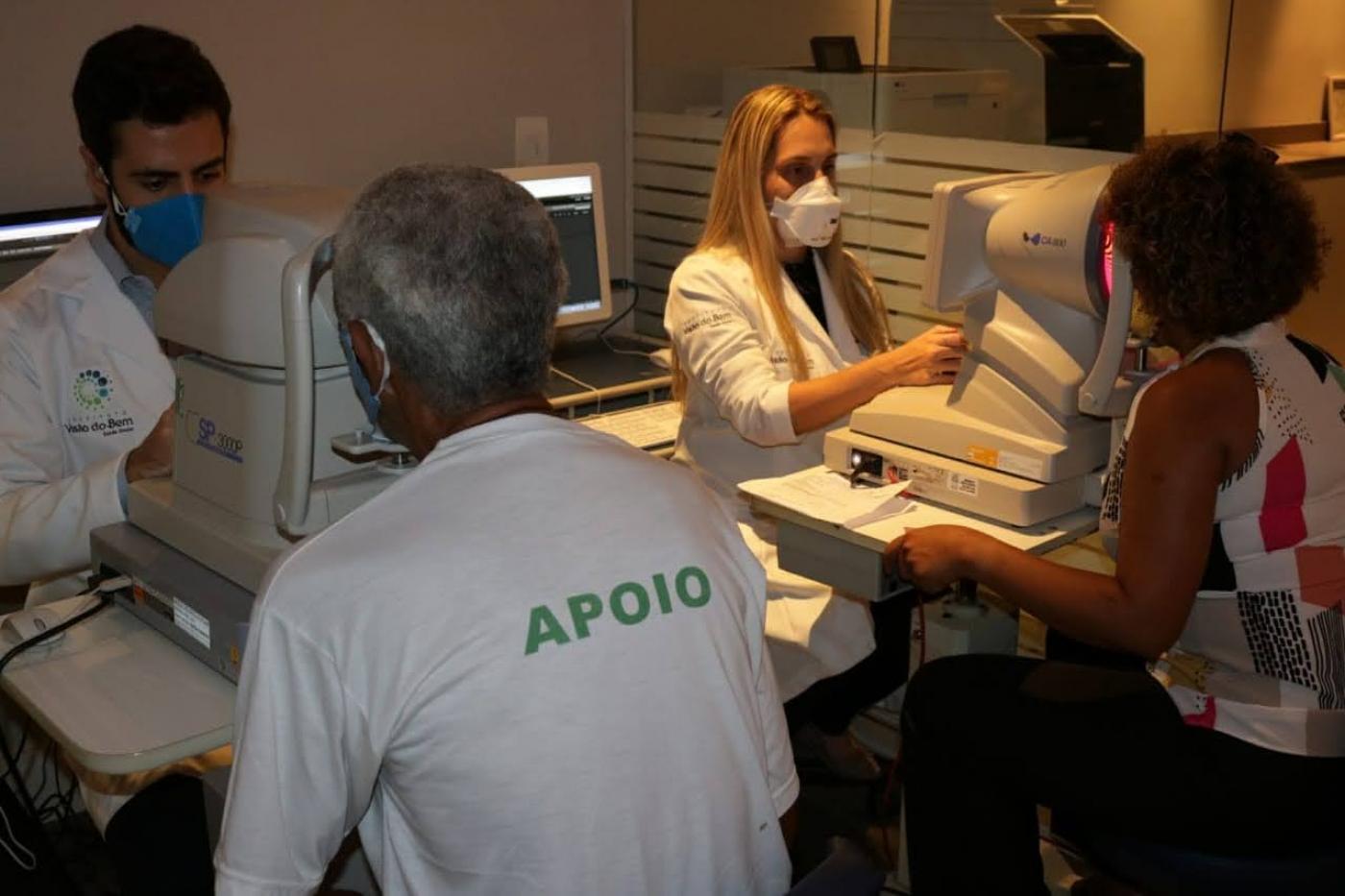 Dias pessoas estão sendo examinadas na frente de aparelhos. #paratodosverem