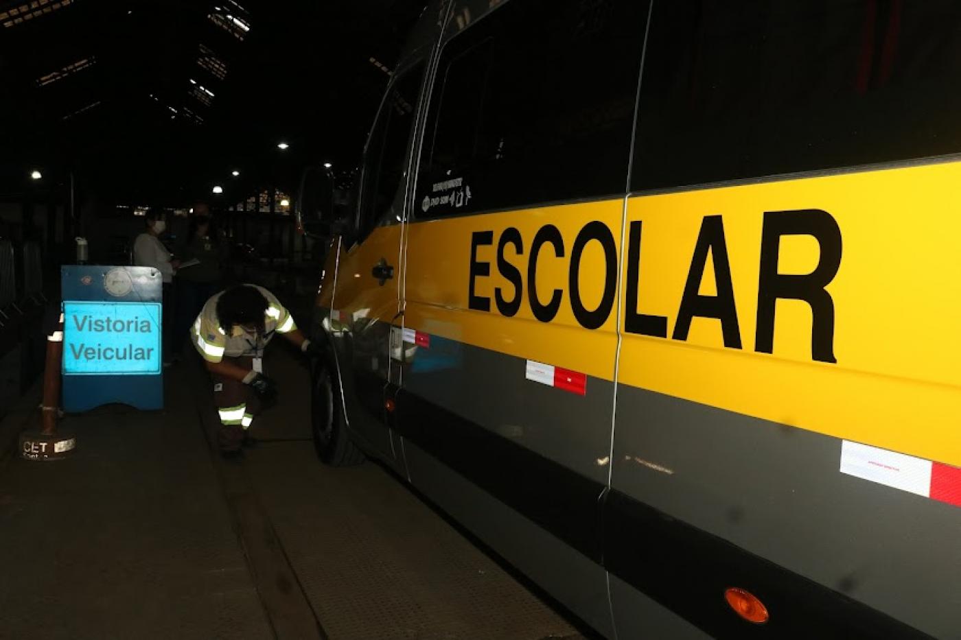 veículo escolar está parado em baia com placa ao lado onde se lê vistoria escolar. #paratodosverem